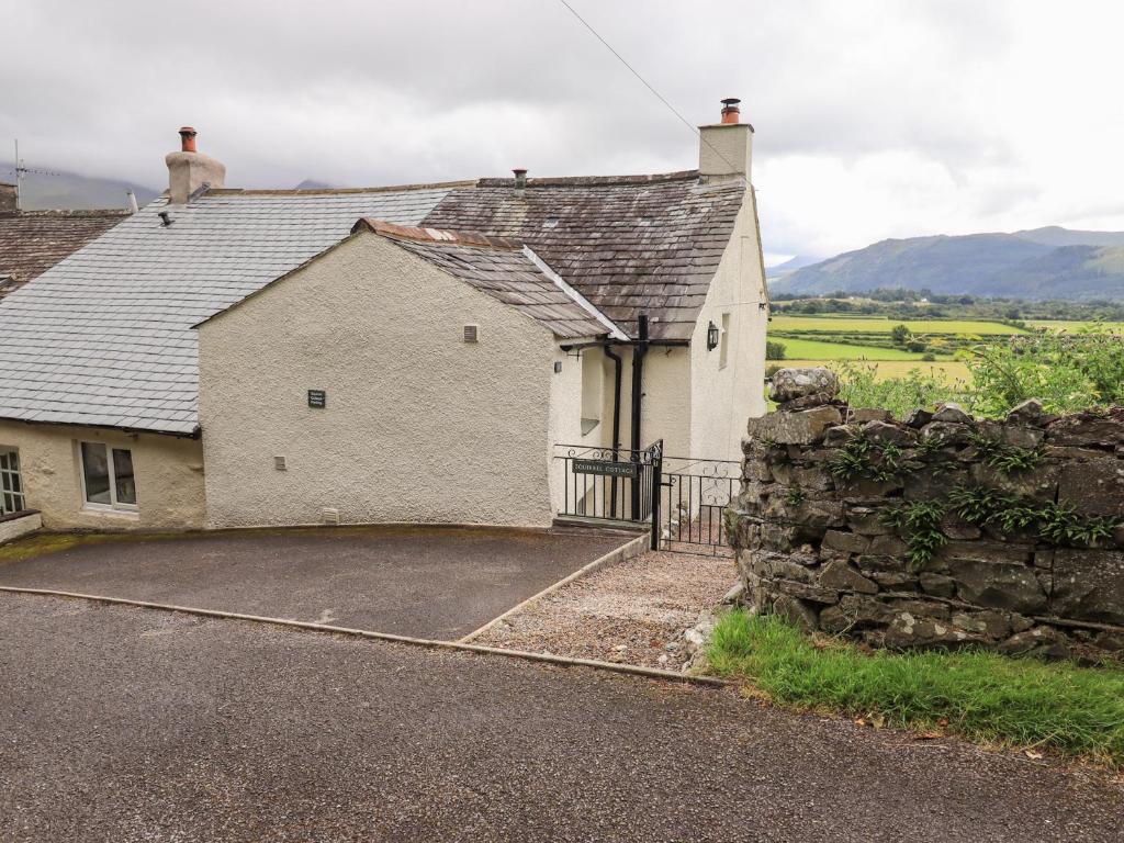 una casa bianca con un muro di pietra e un vialetto di Squirrel Cottage a Keswick