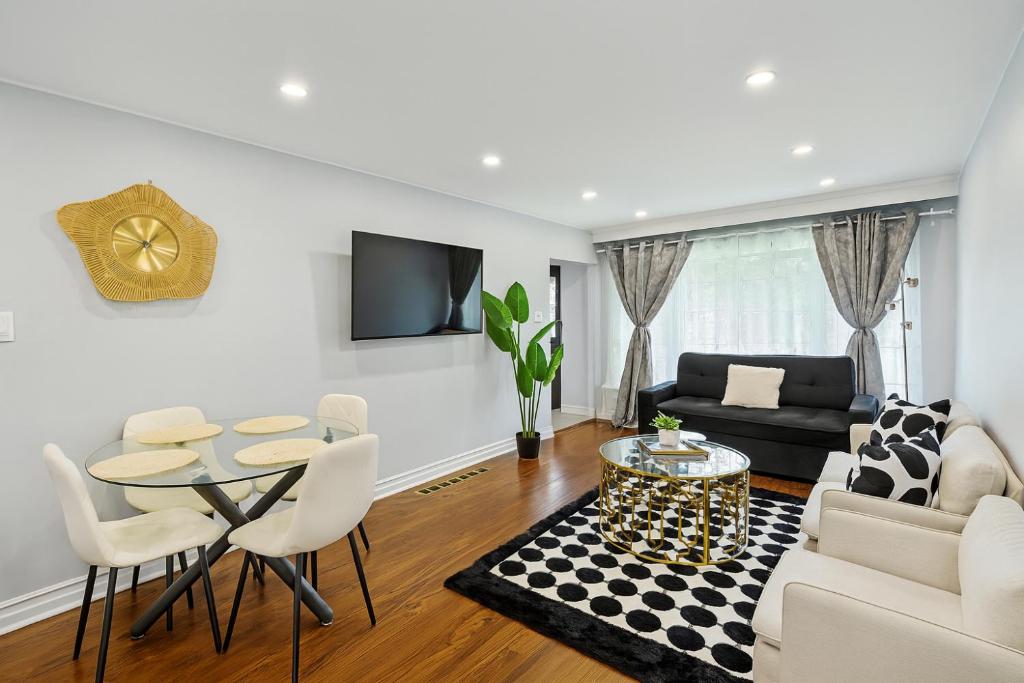 a living room with a table and a couch at Newly Renovated 3BR North York Bungalow with Backyard Patio & Volleyball Set! Close to Rogers Stadium, TTC Subway Access, Perfect for Family Travel, Group Trips or Work Stays! in Toronto
