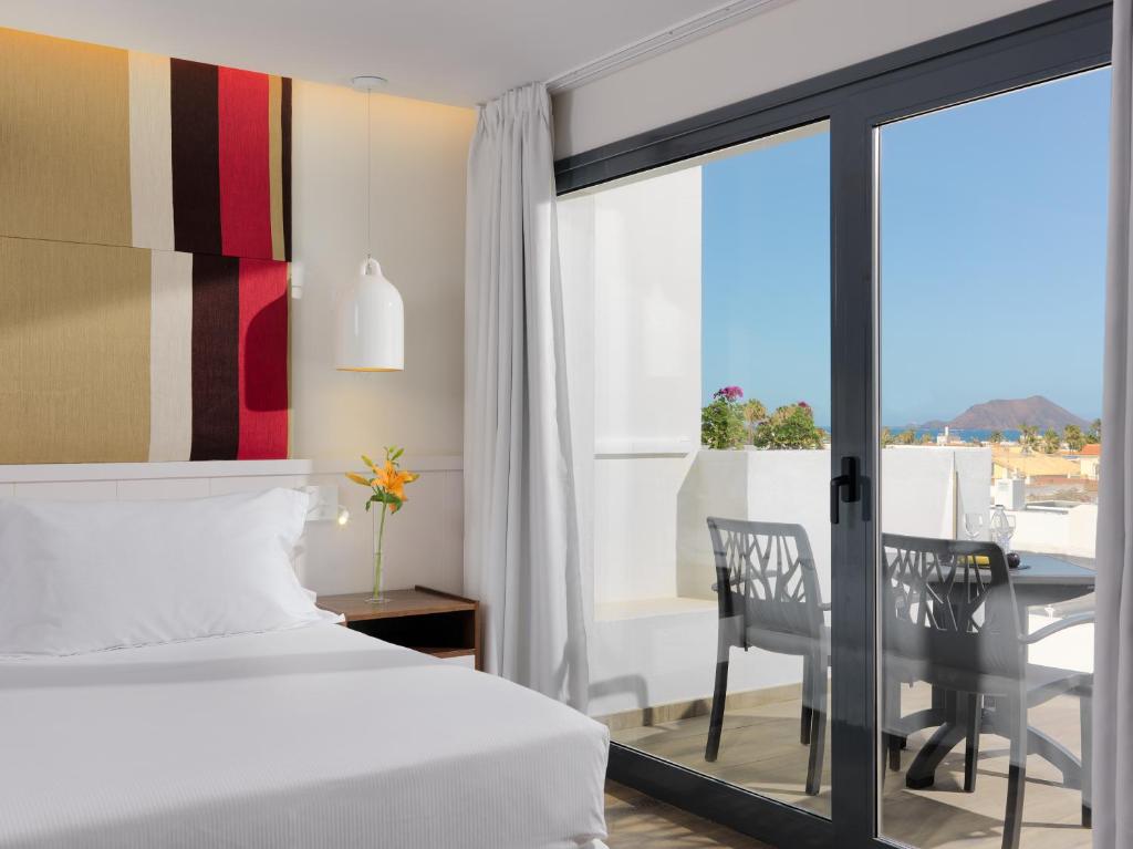 1 dormitorio con cama, mesa y balcón en H10 Ocean Dreams Hotel Boutique - Adults Only en Corralejo