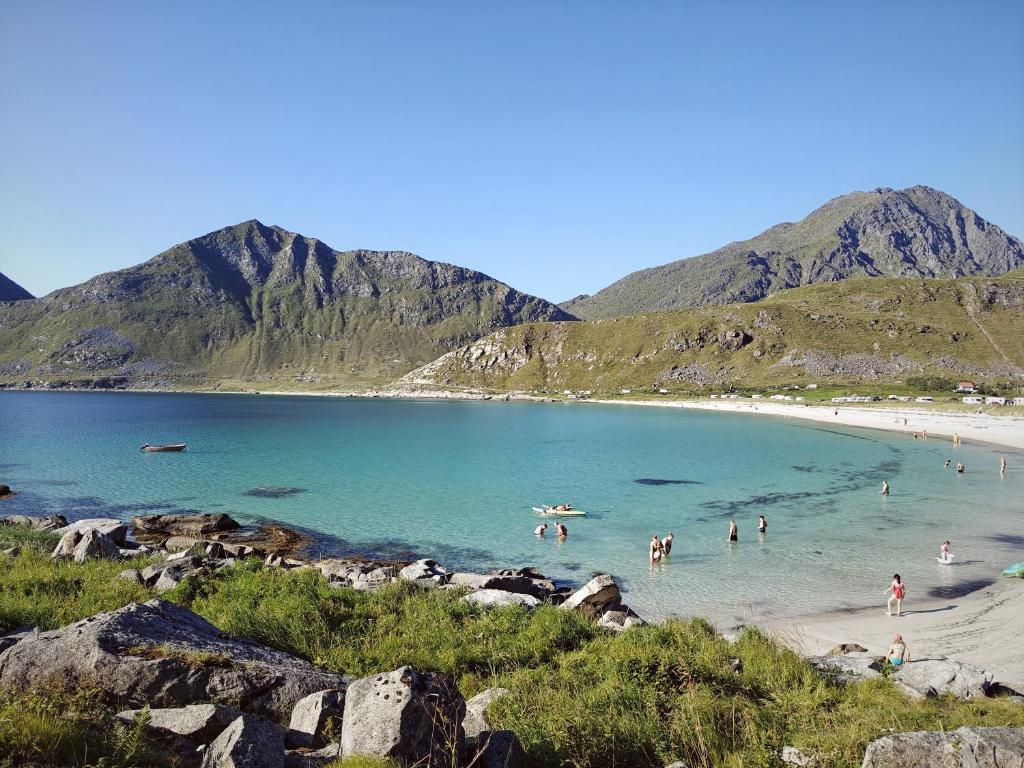 a group of people in the water at a beach at 2 Houses & A Barn Double Room in Vestvågøya