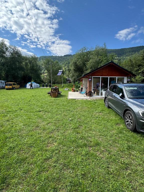 a car parked in the grass in front of a building at Camping -Dor de Munte -Ceahlau in Bistricioara