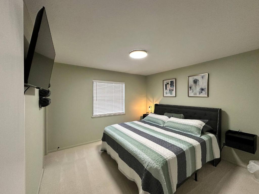 a bedroom with a bed with a striped blanket and a window at Blessed Beyond Measure King with Ensuite in Norwalk