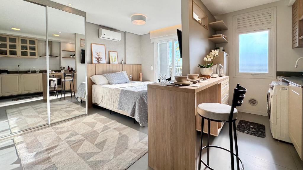 a bedroom with a bed and a kitchen with a counter at Excelente Loft no Quartier in Pelotas