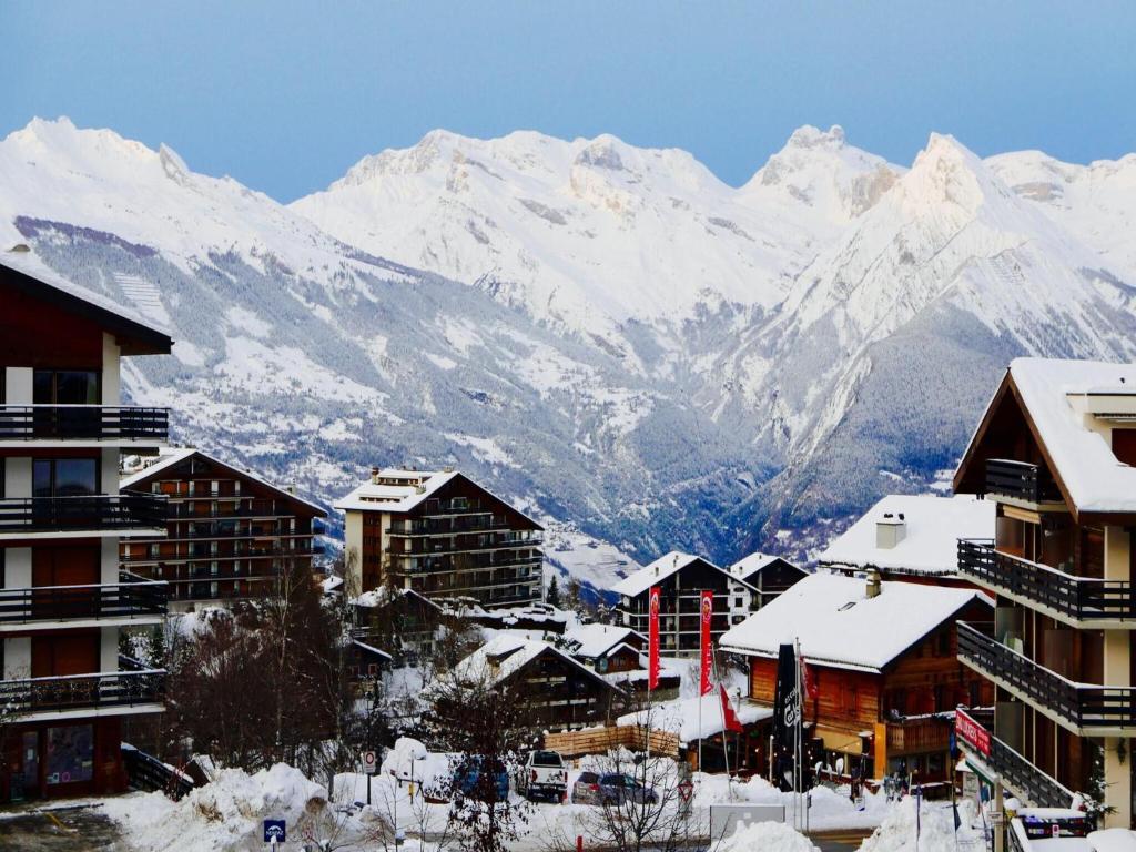 a town with snow covered buildings in front of a mountain at Comfy apartment with terrace in Nendaz