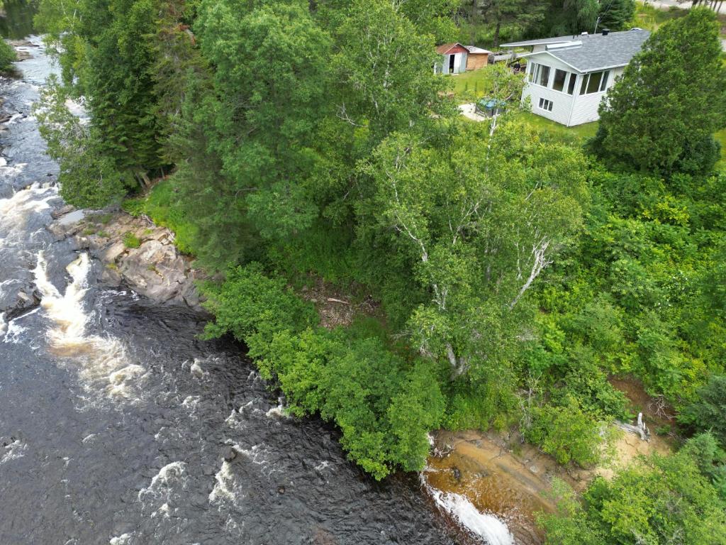 een luchtzicht op een rivier met bomen en een huis bij Le Refuge des Eaux Vives in La Macaza