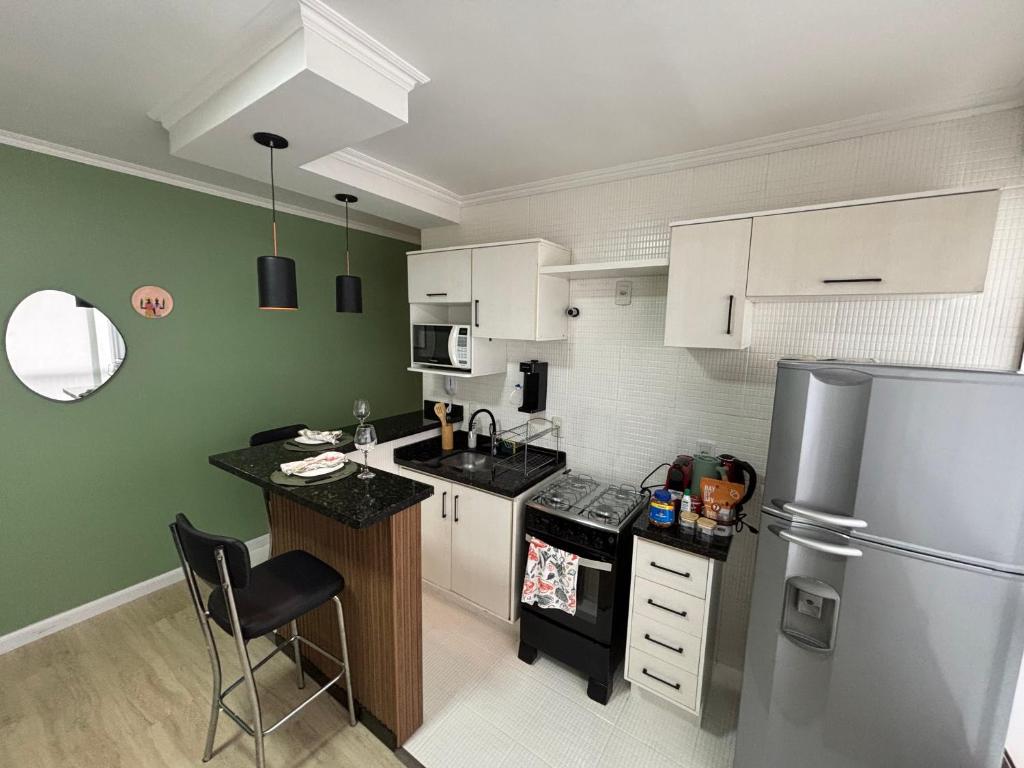 Una cocina con gabinetes blancos y un refrigerador. en Studio Céu de Brasília, en Brasilia