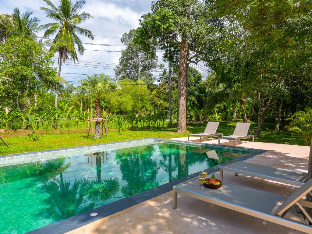 ein Swimmingpool mit zwei Stühlen und einem Tisch daneben in der Unterkunft Tropical Nusa Residence in Koh Samui 