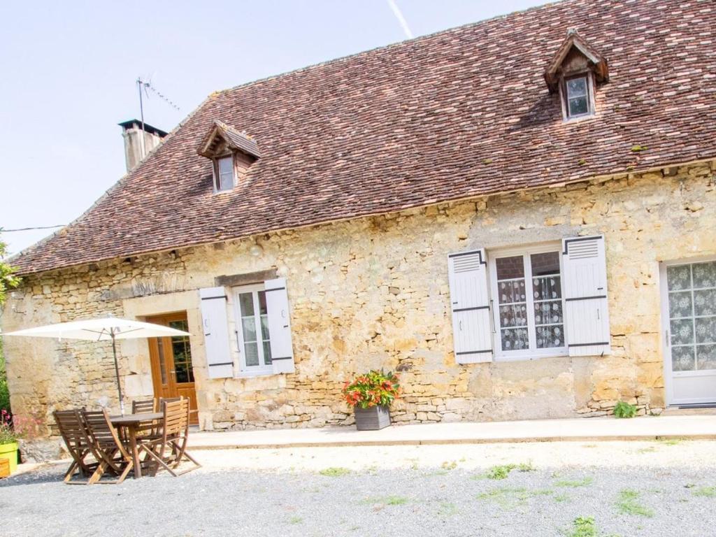 an old stone building with a table and an umbrella at Maison de Charme avec Jardin, Activités de Plein Air et Proche Sites Touristiques - FR-1-616-333 in Tourtoirac