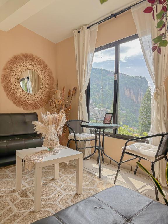 a living room with a couch and a table and a window at Departamento Santa Fe (totalmente nuevo) in Taxco de Alarcón