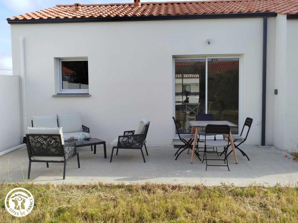 Charmant gîte avec terrasse à La Barre-de-Monts - FR-1-426-586 في لا باريه دي مونت: فناء مع طاولة وكراسي بجوار مبنى