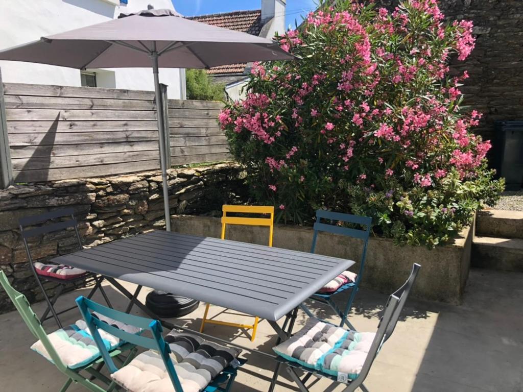 a table and chairs with an umbrella and flowers at Chaleureuse Maison à Groix, 5 pers, 3 chambres - FR-1-813-31 in Groix