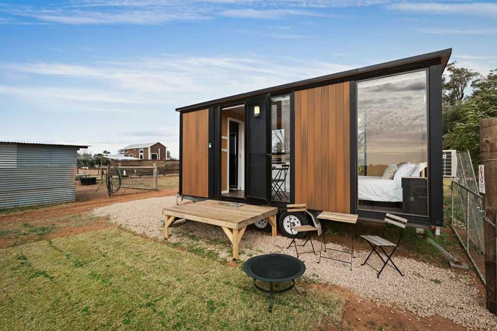 a tiny house with a large window and a bed at Bluestone Alpacas Theodores Corner by Tiny Away in Cabarita