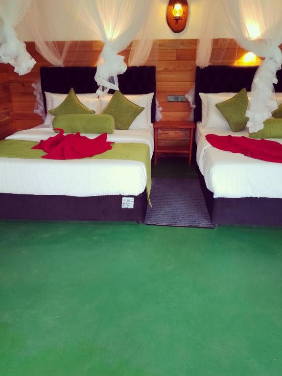 two beds in a room with green flooring at Serenity cottage in Ella