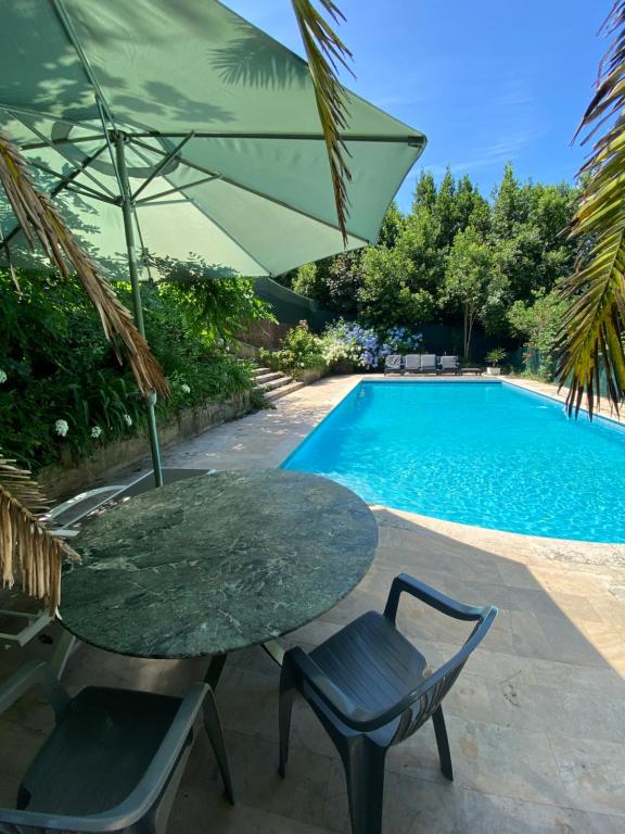 a table and chairs with an umbrella next to a swimming pool at VILLA BIARRITZ 1923 private pool in Biarritz