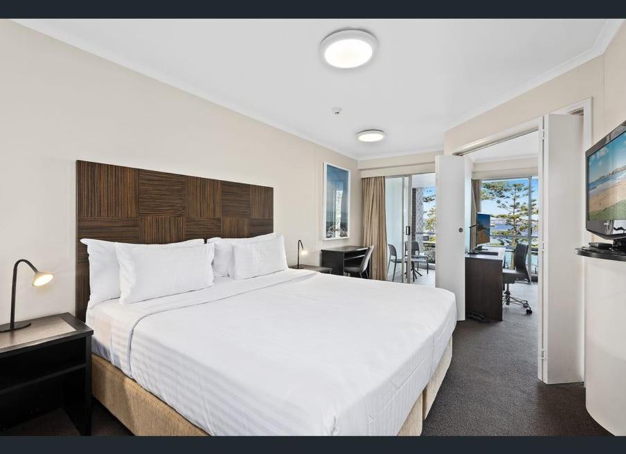 a bedroom with a large white bed and a desk at Grande Esplanade Manly Central in Sydney