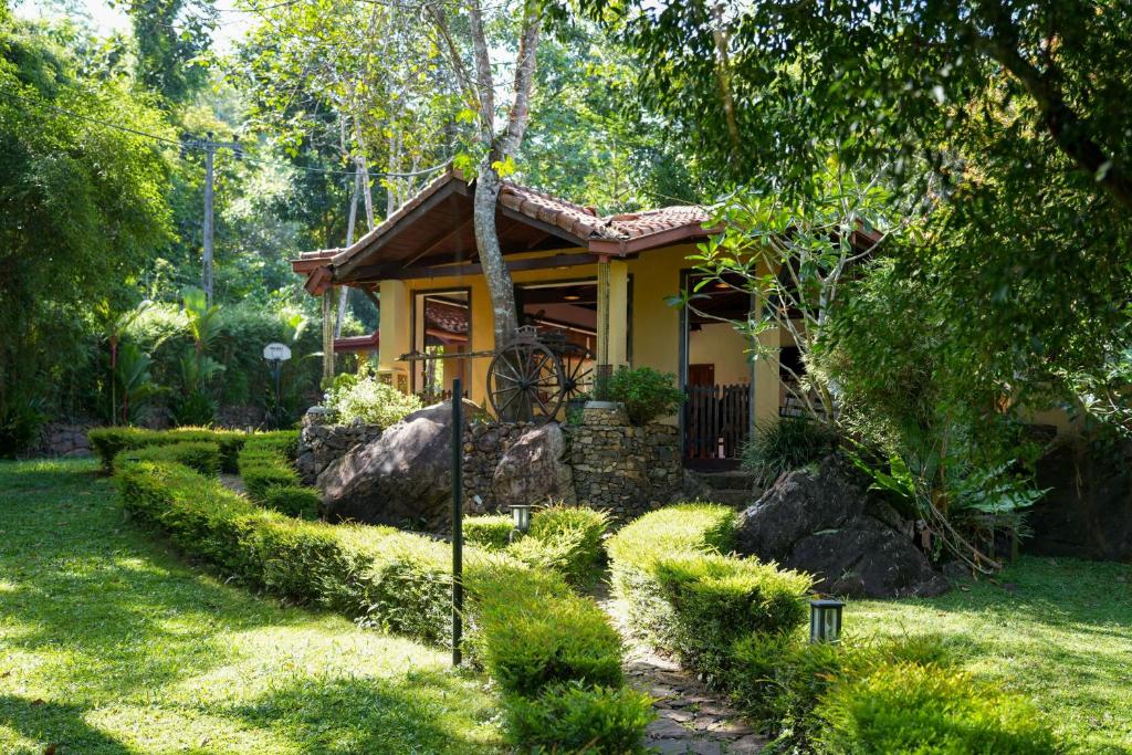 une petite maison jaune au milieu d'une cour dans l'établissement Tappers' Village Nature Resort & Retreat Centre, Kiriella, à Ratnapura