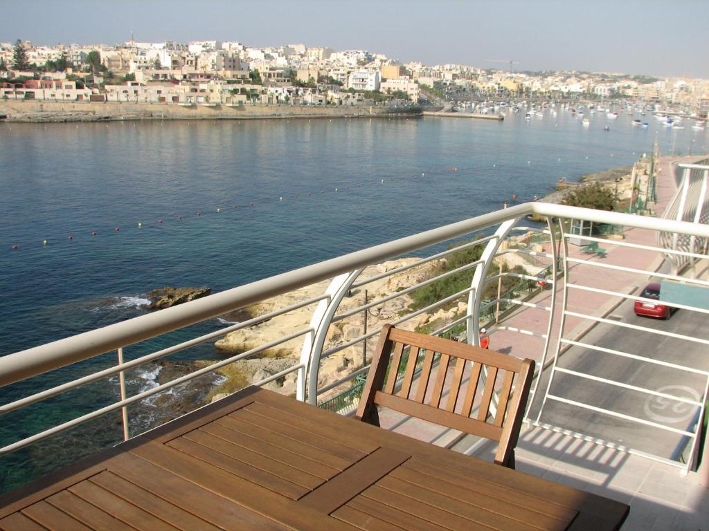 a balcony with a table and chair on a ship at SeaFront Apartment Marsascala in Marsaskala