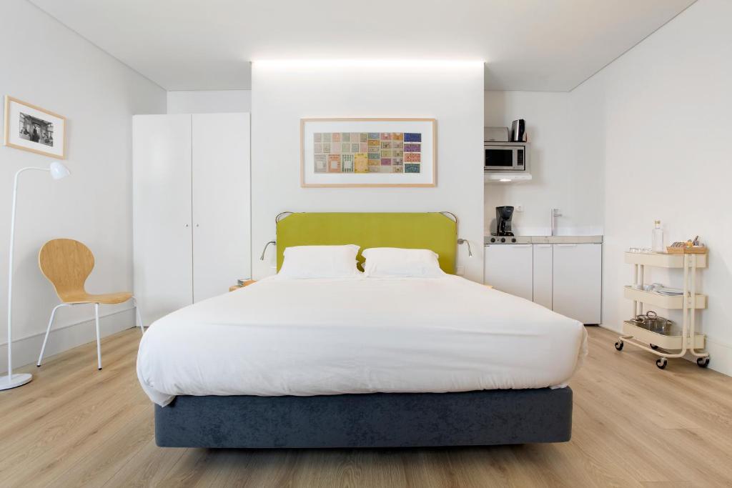 a bedroom with a large bed and a chair at LSA Ascensor da Bica by Numa in Lisbon