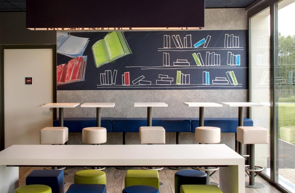 a classroom with tables and chairs and a wall with books at ibis budget Montceau les Mines in Montceau-les-Mines