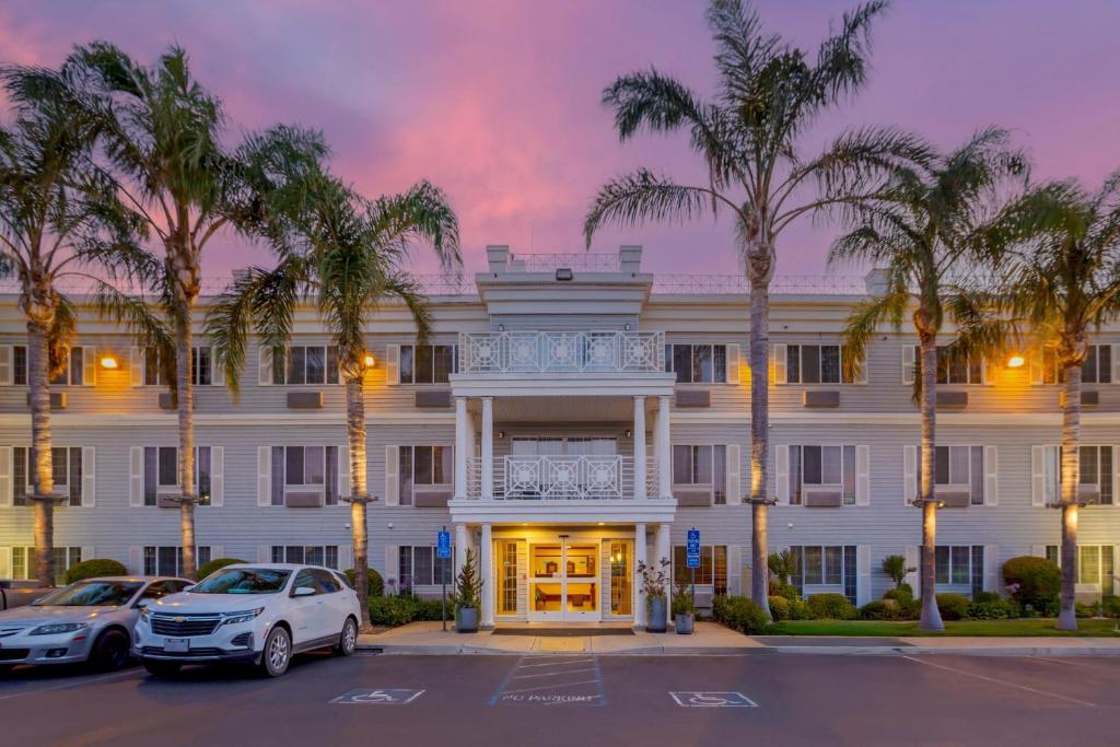 a large white building with palm trees in a parking lot at Best Western Luxury Inn in Tracy