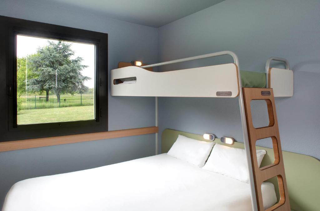 a bedroom with a bunk bed and a window at ibis budget Montceau les Mines in Montceau-les-Mines