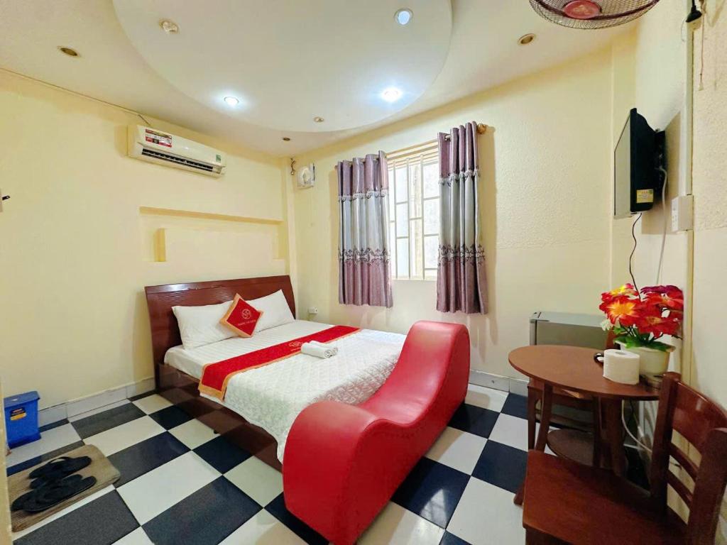 a bedroom with a bed and a red chair at Khách Sạn Ngọc Hà in Ho Chi Minh City