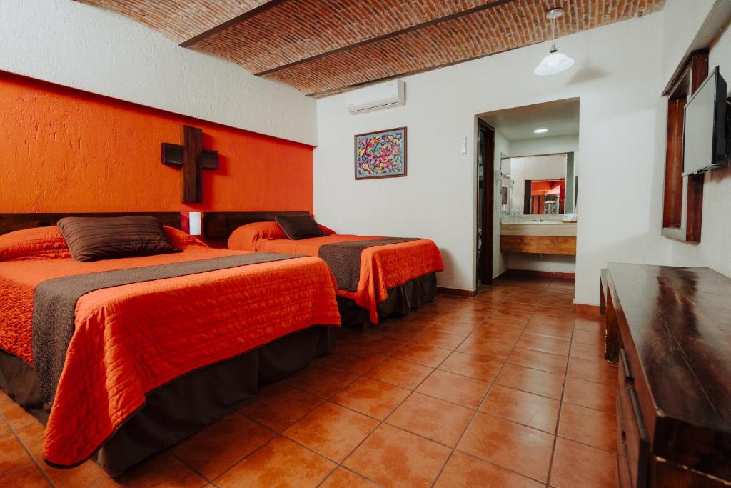 two beds in a room with orange walls at Hotel Mesón de los Cristeros 