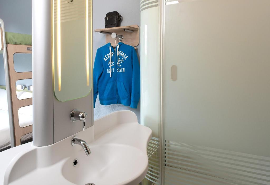 a bathroom with a white sink and a blue shirt at ibis budget Montceau les Mines in Montceau-les-Mines
