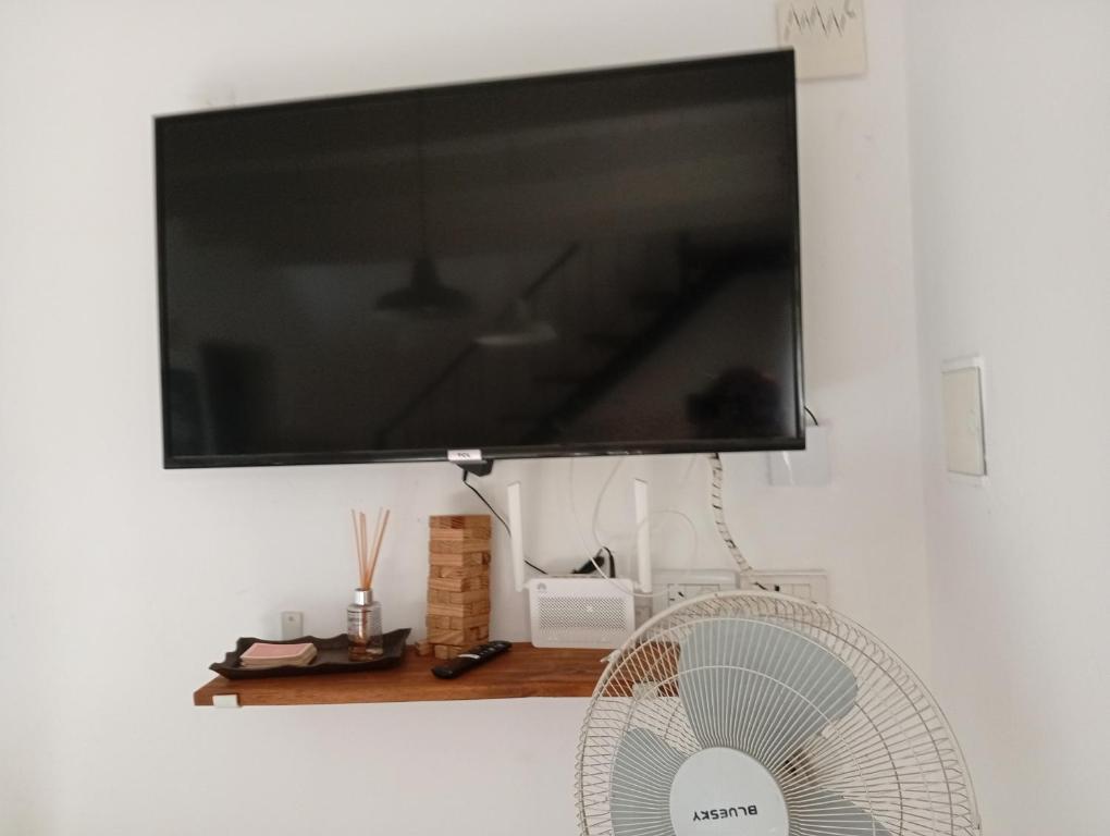 TV de pantalla plana colgada en una pared con ventilador en Tea Amoro Apart Duplex con aire acondicionado, en Tandil