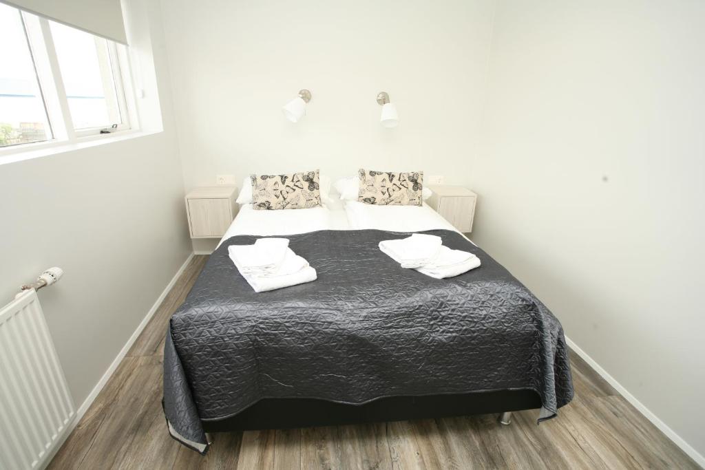 a bedroom with a bed with black blanket and white towels at Skýjaborg Apartments in Höfn
