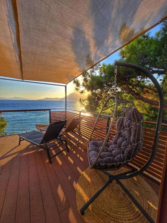 a porch with two chairs and a swing at Vista Mare in Kámpos