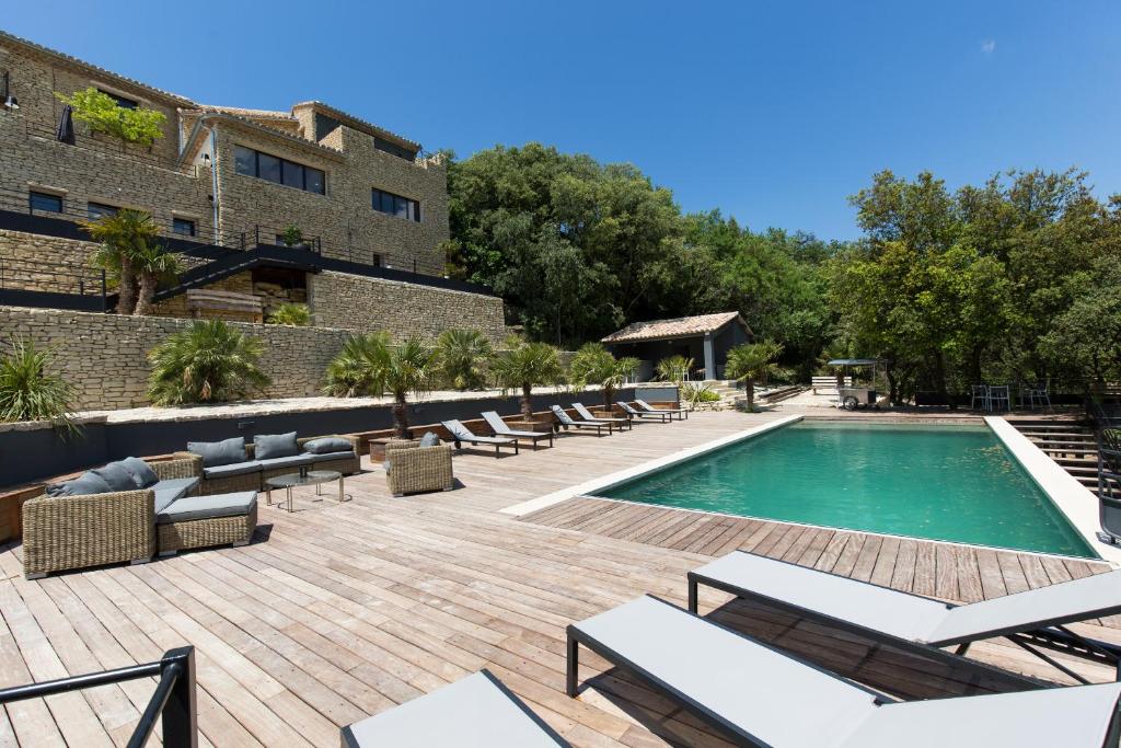 uma piscina com espreguiçadeiras e um edifício em Hôtel La Maison de Crillon em Crillon-le-Brave