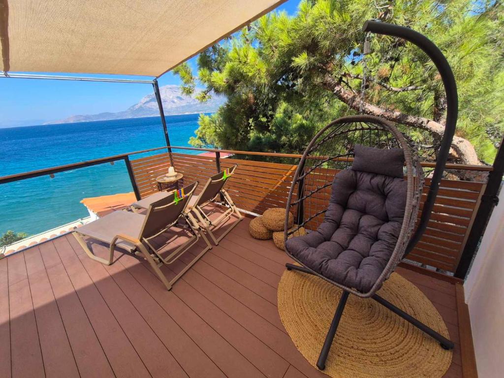 a porch with a wicker chair on a deck with the ocean at Vista Mare in Kámpos