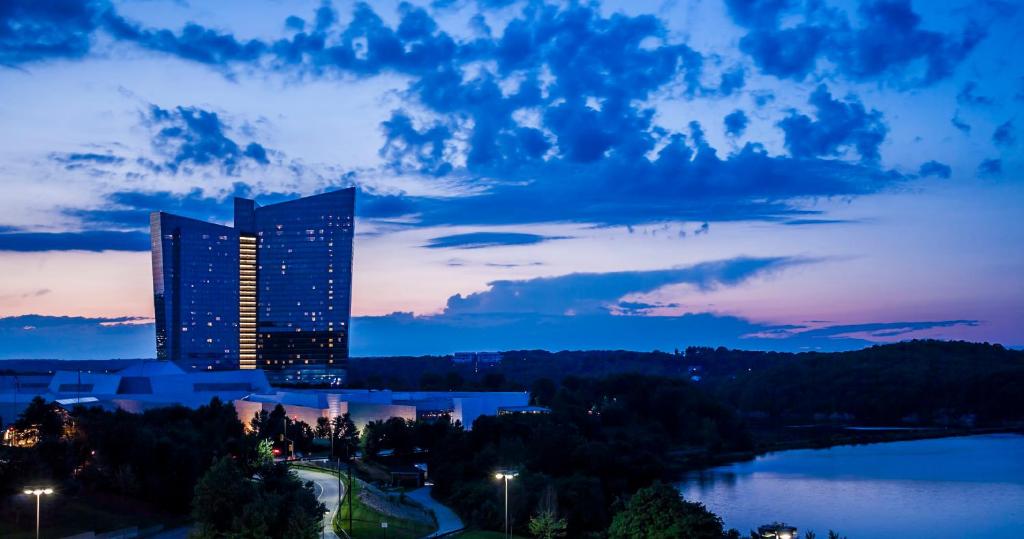 un edificio alto con luces encendidas frente a un lago en Mohegan Sun en Uncasville