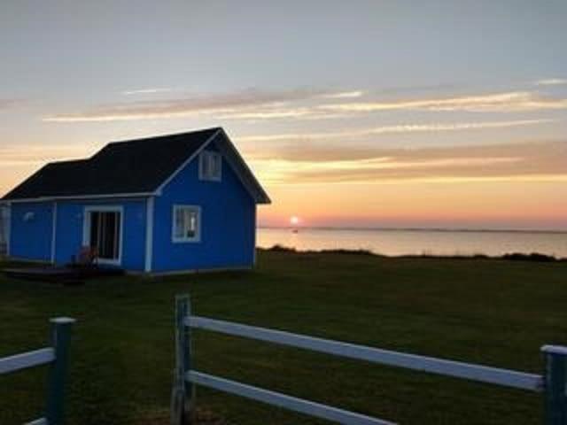 une maison bleue dans un champ avec une clôture dans l'établissement Coastal Charm Beach Nearby - Chalet Poirier, à Fatima