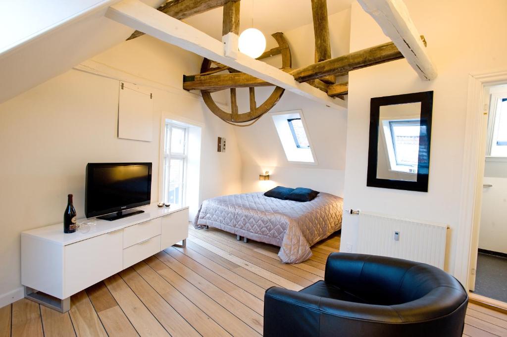 1 dormitorio con 1 cama, TV y sofá en Den Gamle Købmandsgaard Bed & Breakfast, en Ribe