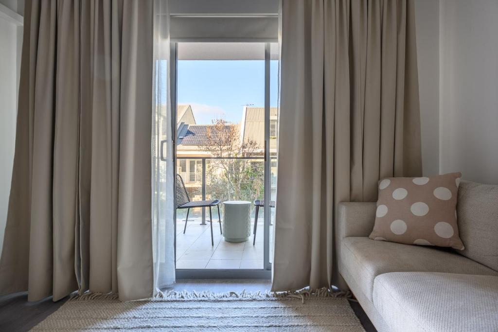 Una sala de estar con un sofá y una puerta corrediza de vidrio. en 104 EastPerth Euphoria Escape 2BR Parkng, en Perth