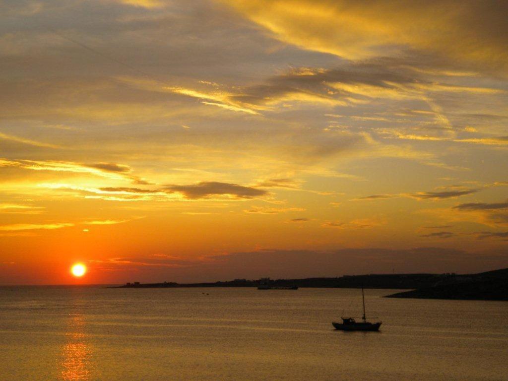 a boat in the water at sunset at Hotel Paros in Parikia