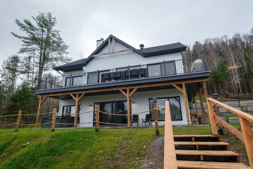a house with a wrap around porch with a deck at Spa & Pure Relaxation - Chalet Saint-Cerf in Saint Come