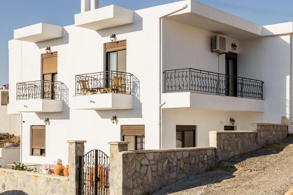a white building with balconies and a wall at Gina's house in Asklipiḯon