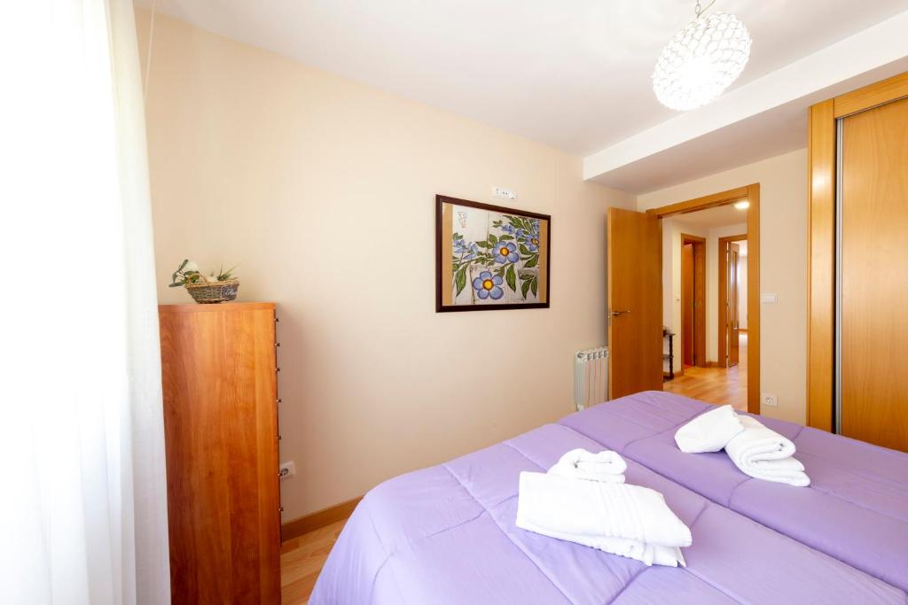 a bedroom with a purple bed with towels on it at Casa Venerable Carabantes in Soria