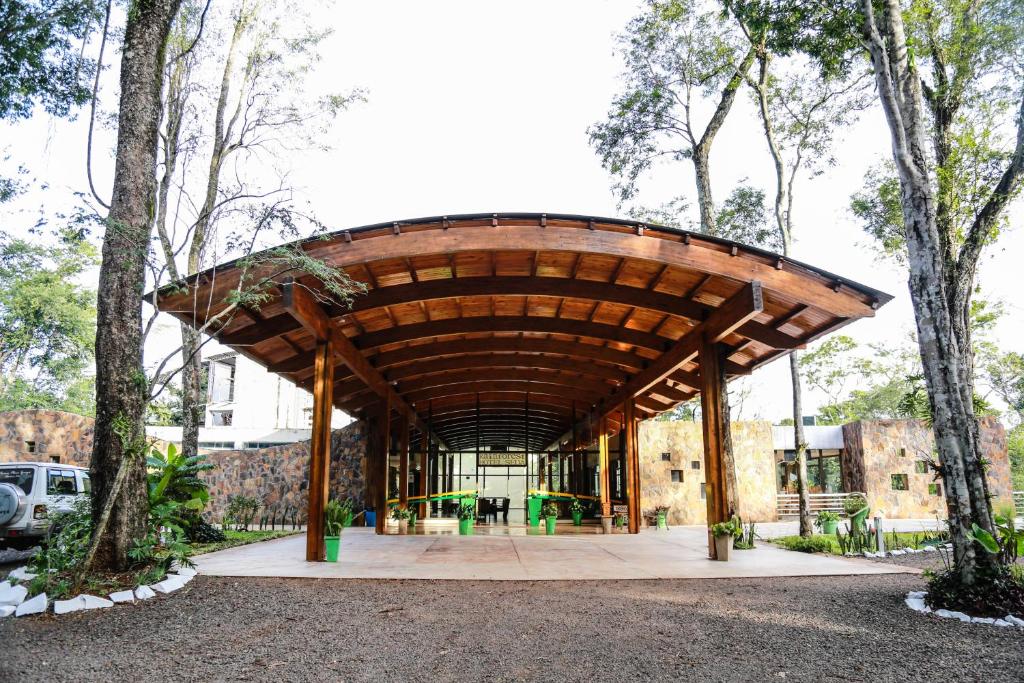 a building with a wooden roof in the middle of trees at Rainforest Hotel & Cabañas in Puerto Iguazú