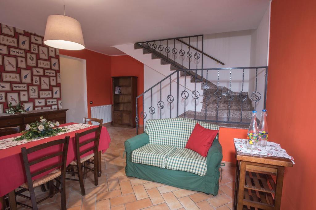 sala de estar con sofá, mesa y escalera en Casale Godenza, en Matelica