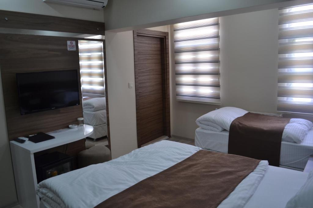 una camera d'albergo con due letti e una televisione di Divrigi Kosk Hotel a Divriği