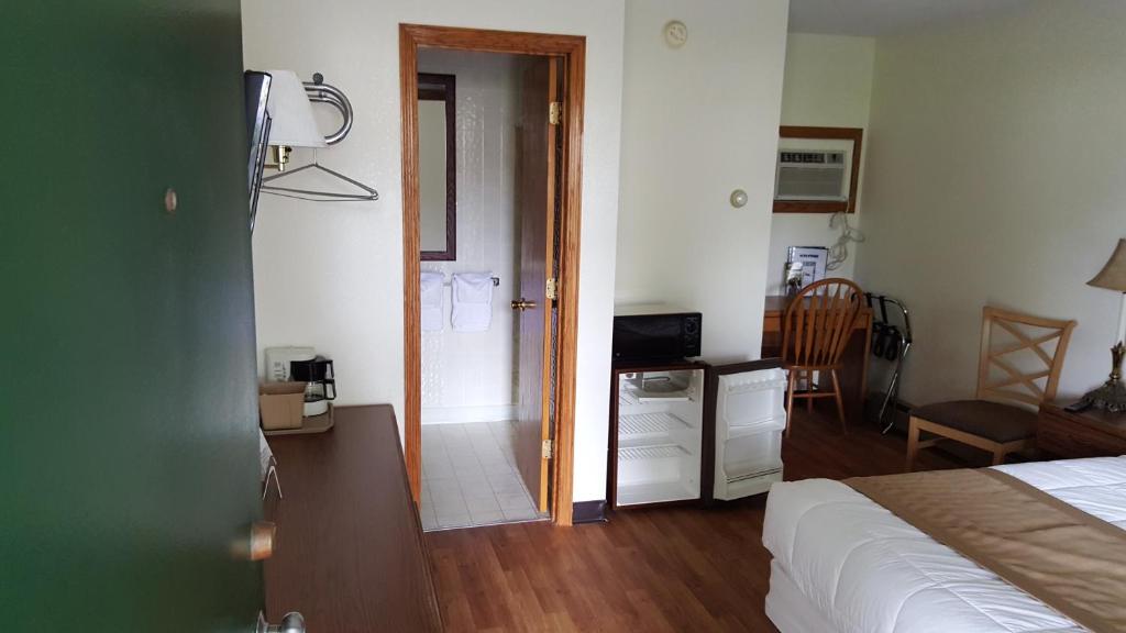 1 dormitorio con 1 cama y puerta que conduce a un baño en Budget Host Inn, en Detroit Lakes