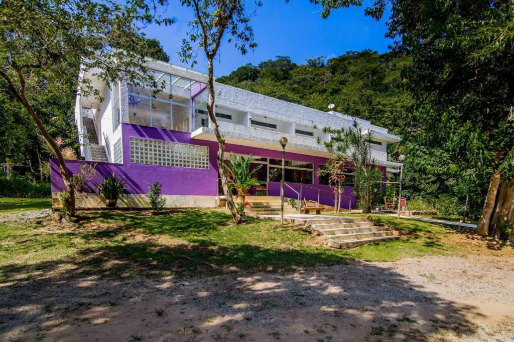 a house with purple paint on the side of it at Casa Bacarirá - Floresta com Yoga e Café da Manhã Vegano in Camburi