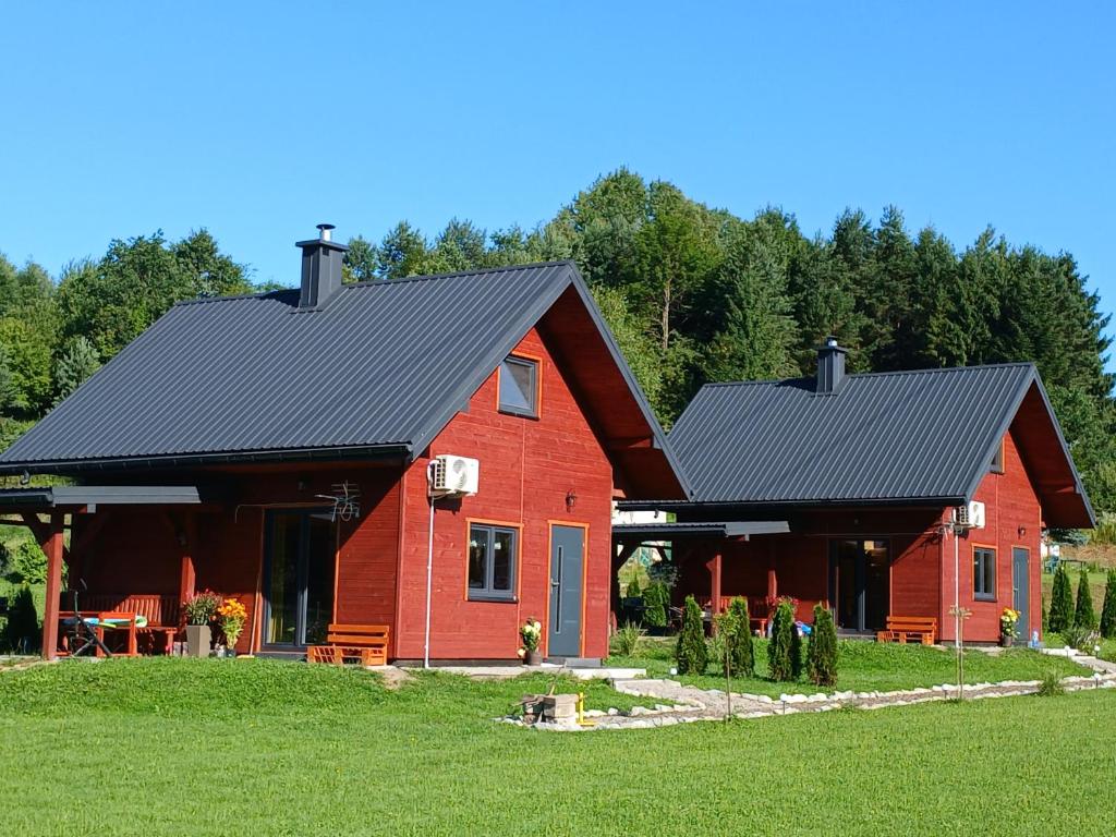 a red barn with a black roof at Domki pod szybowiskiem in Lesko