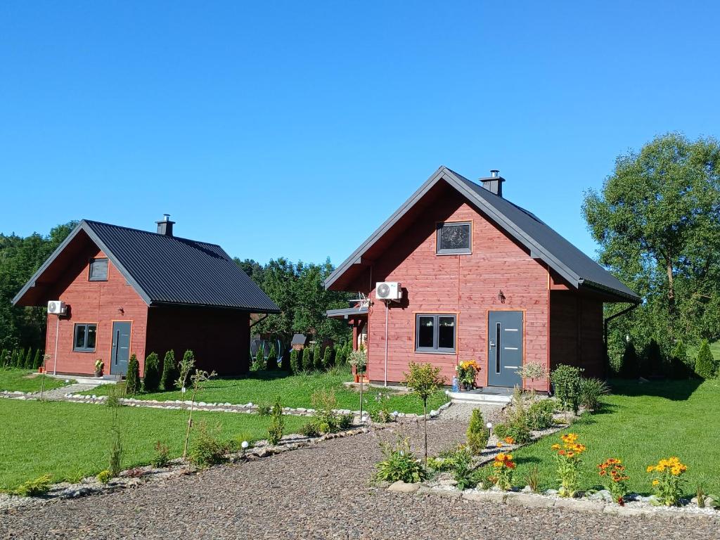 a red house with a black roof and a garden at Domki pod szybowiskiem in Lesko