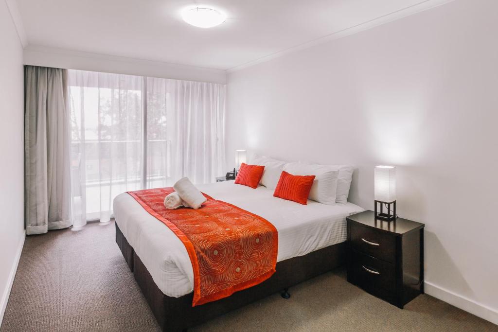 1 dormitorio con 1 cama grande con almohadas de color naranja en Newcastle Central Plaza Apartment Hotel Official, en Newcastle