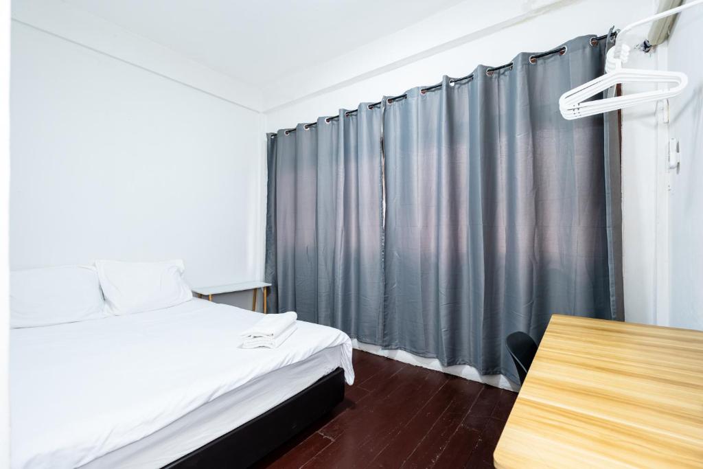 1 dormitorio con cama, mesa y cortina en XX GO INN Siriraj Wang Lang - โก อินน์ โรงพยาบาลศิริราช วังหลัง, en Bangkok